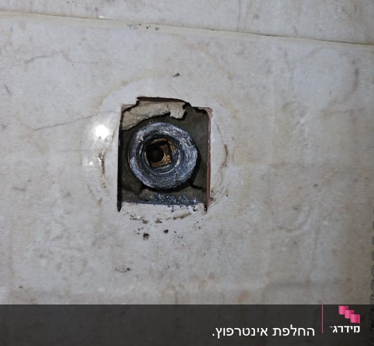 צינור מים חשוף בקיר עם חור